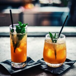 Two chilled cocktails with mint and ice on a bar counter, garnished with fresh mint leaves.